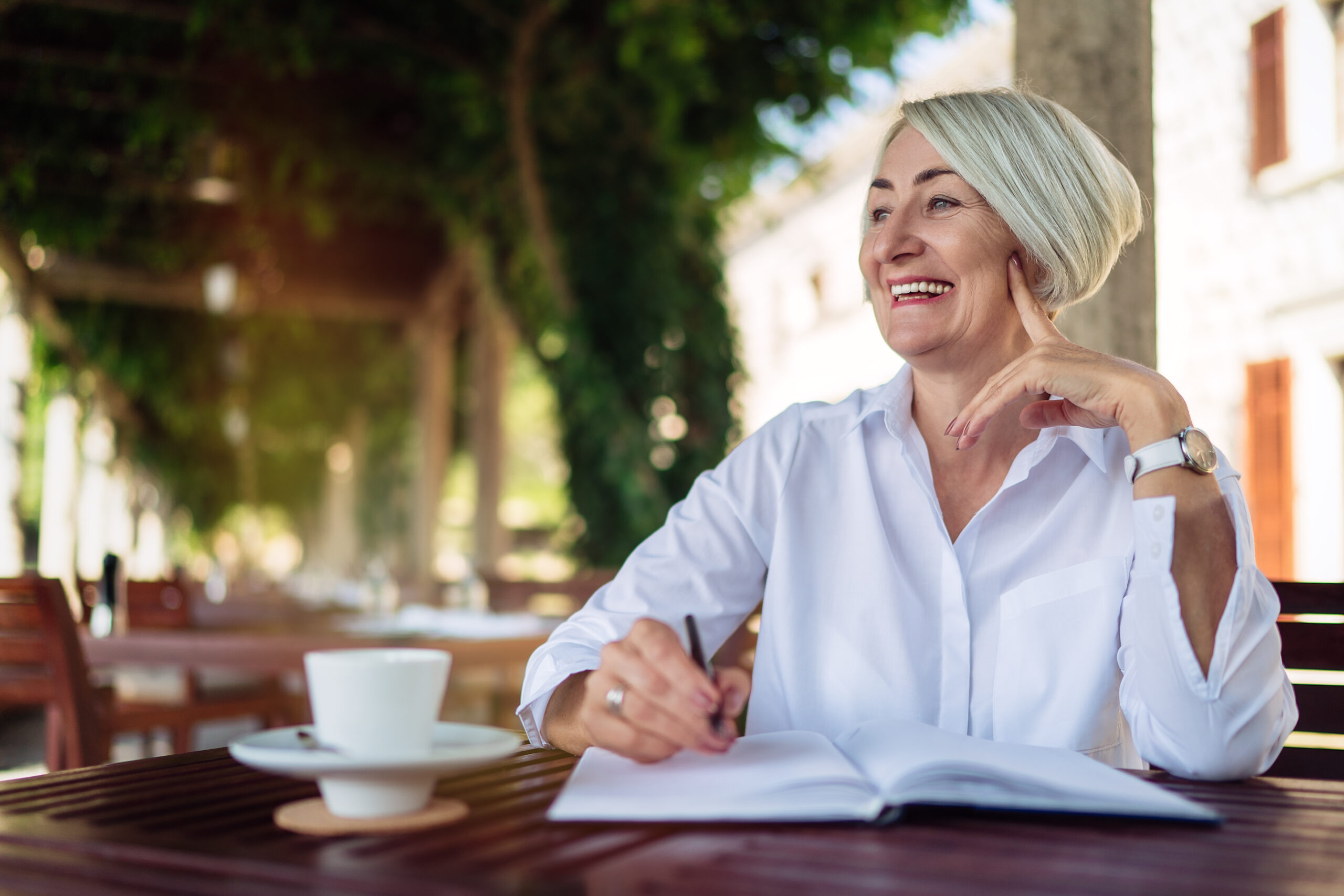 Mujer sonriendo y bebiendo café en una mesa al aire libre